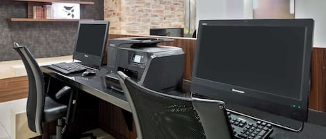 A modern office space with two desktop computers, a printer, and a keyboard on a desk.