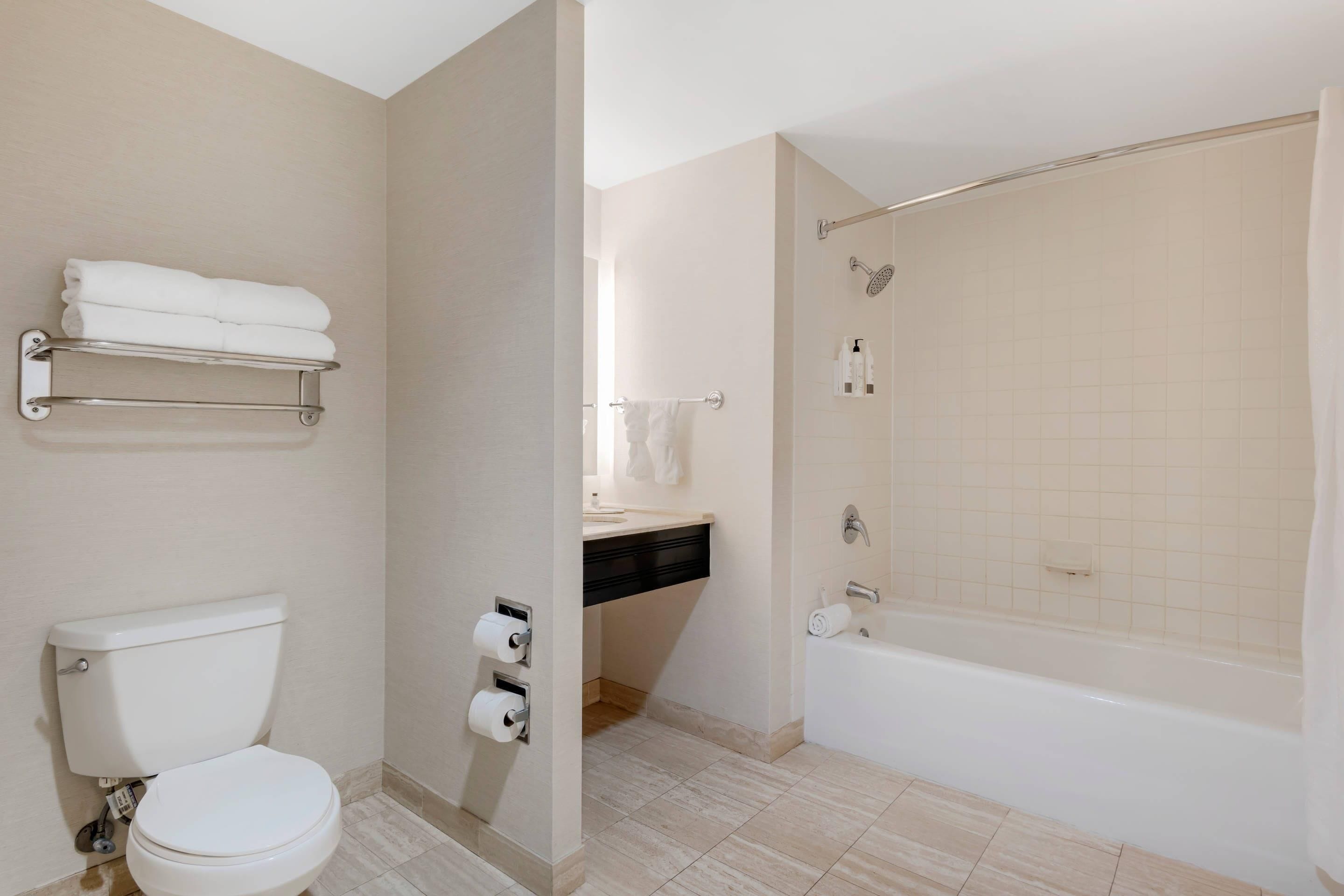 A modern bathroom with a toilet, towel rack, shower, and bathtub.
