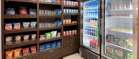 A snack and beverage section with shelves stocked with various chips, snacks, and bottled drinks.