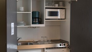 Une petite cuisine équipée d’un four à micro-ondes, d’une machine à café et d’un évier.