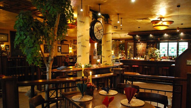 Un restaurant avec des tables et des chaises en bois, et une grande horloge au mur.