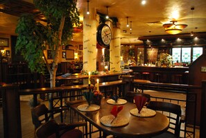 Un restaurant avec des tables et des chaises en bois, et une grande horloge au mur.