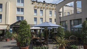Un espace extérieur aménagé avec des tables et des chaises, entouré de plantes en pot.