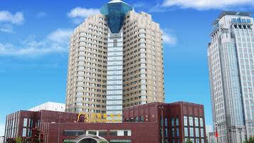 A modern hotel building with a prominent glass facade and a traditional red exterior.