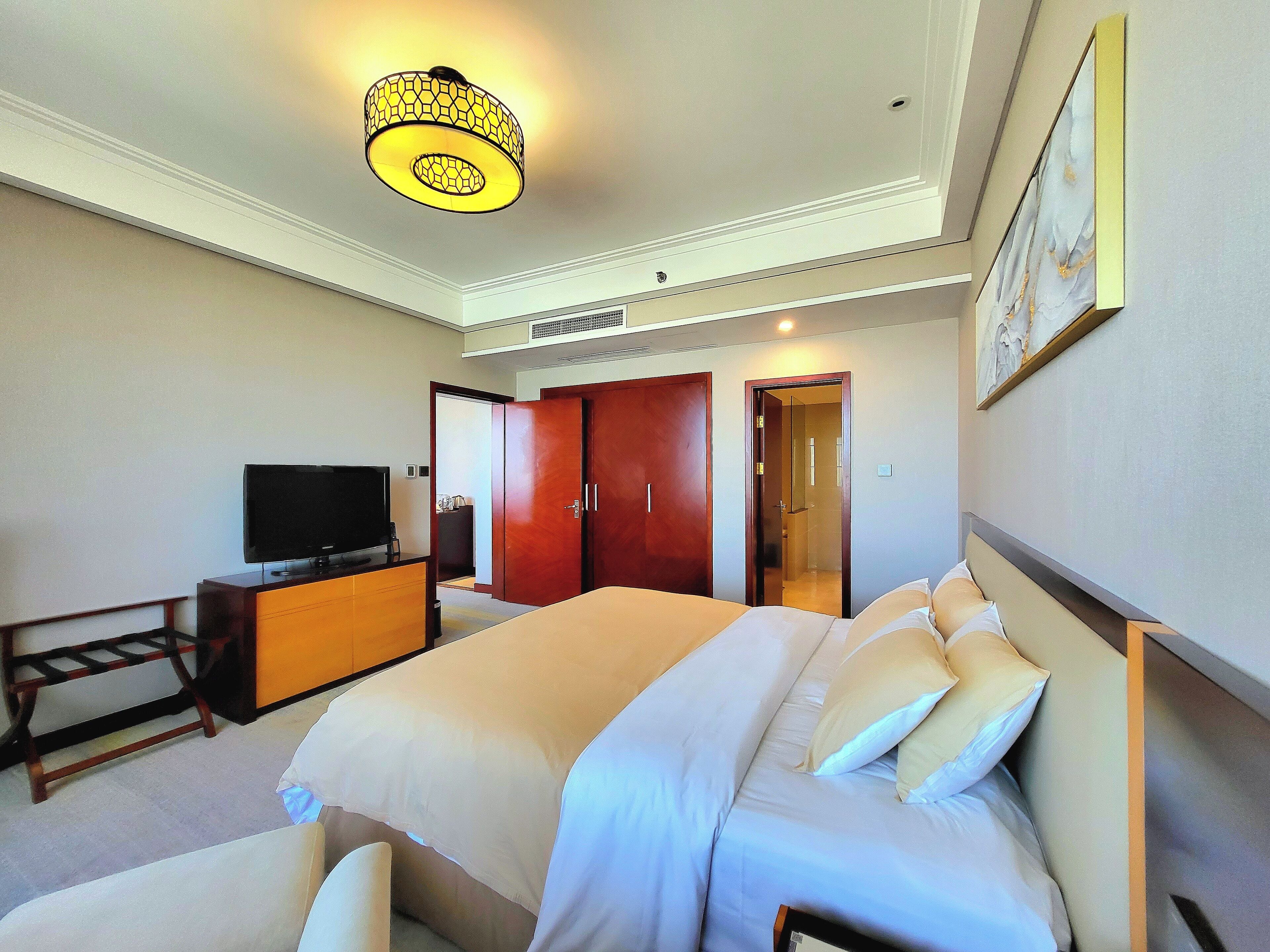 Une chambre d’hôtel comprenant un lit, une télévision, une commode et une porte donnant sur une salle de bain.