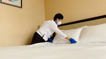 Una persona arreglando una cama en una habitación de hotel.