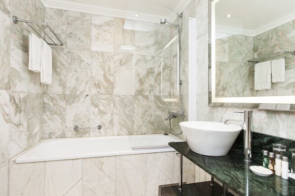 A modern bathroom with a marble wall, a freestanding bathtub, a sink with a mirror, and a towel rack. - Elite Plaza Hotel Malmö (Malmö)