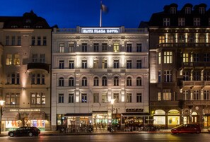 Ein historisches Gebäude mit einem zentralen Eingang, mehreren Stockwerken und einer Fahnenstange.