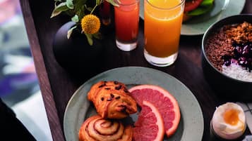 A tray with breakfast items including croissants, grapefruit slices, a sandwich, and a bowl of cereal.