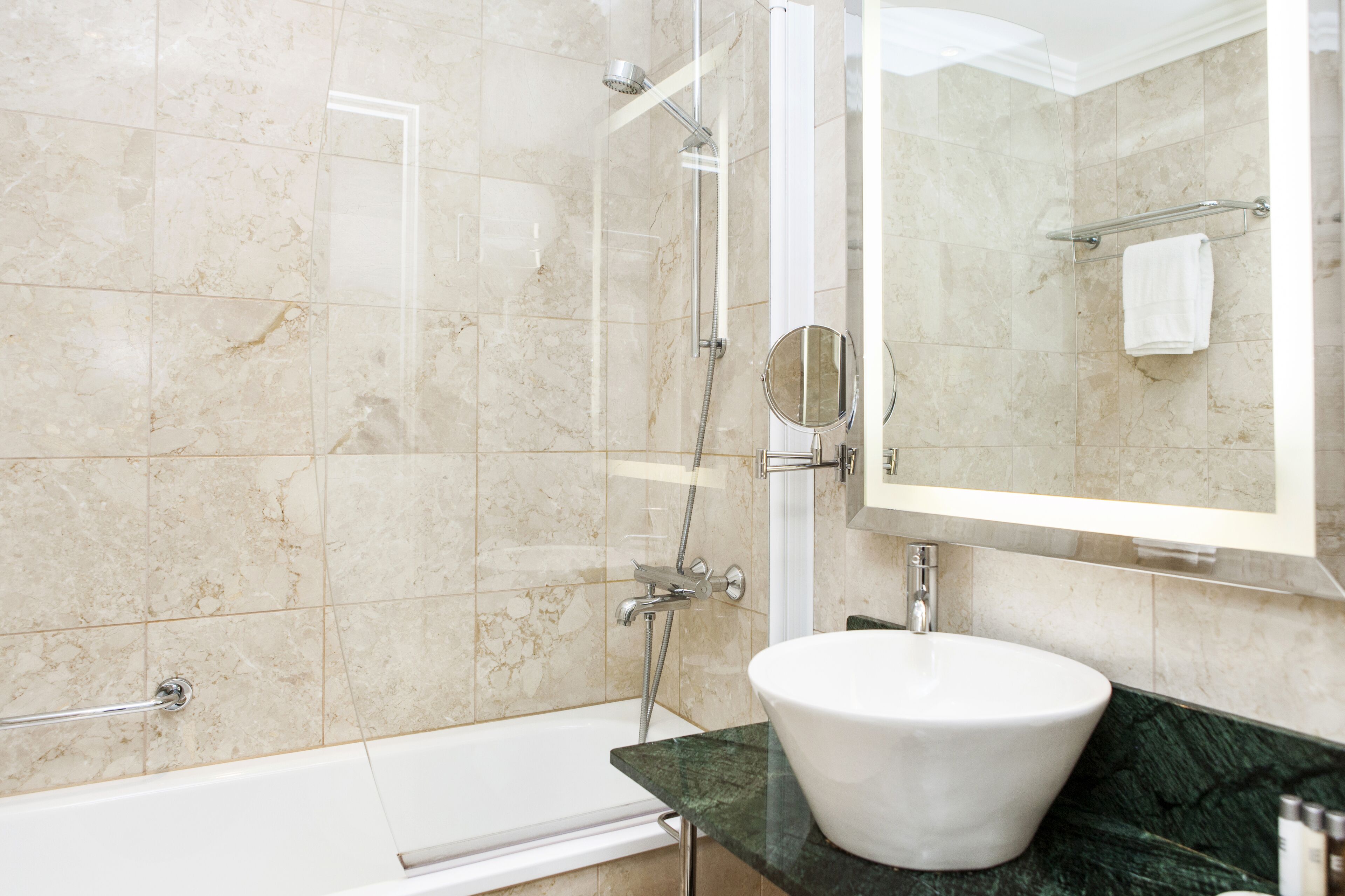 A modern bathroom with a bathtub, a shower, a sink, and a large mirror.