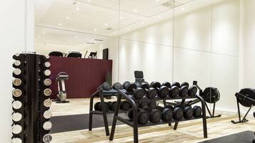Une salle de sport équipée de matériel d’exercice, un comptoir d’accueil et un grand miroir.