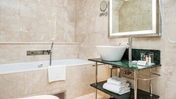 A modern bathroom with a bathtub, a large mirror, and a vanity with a sink.