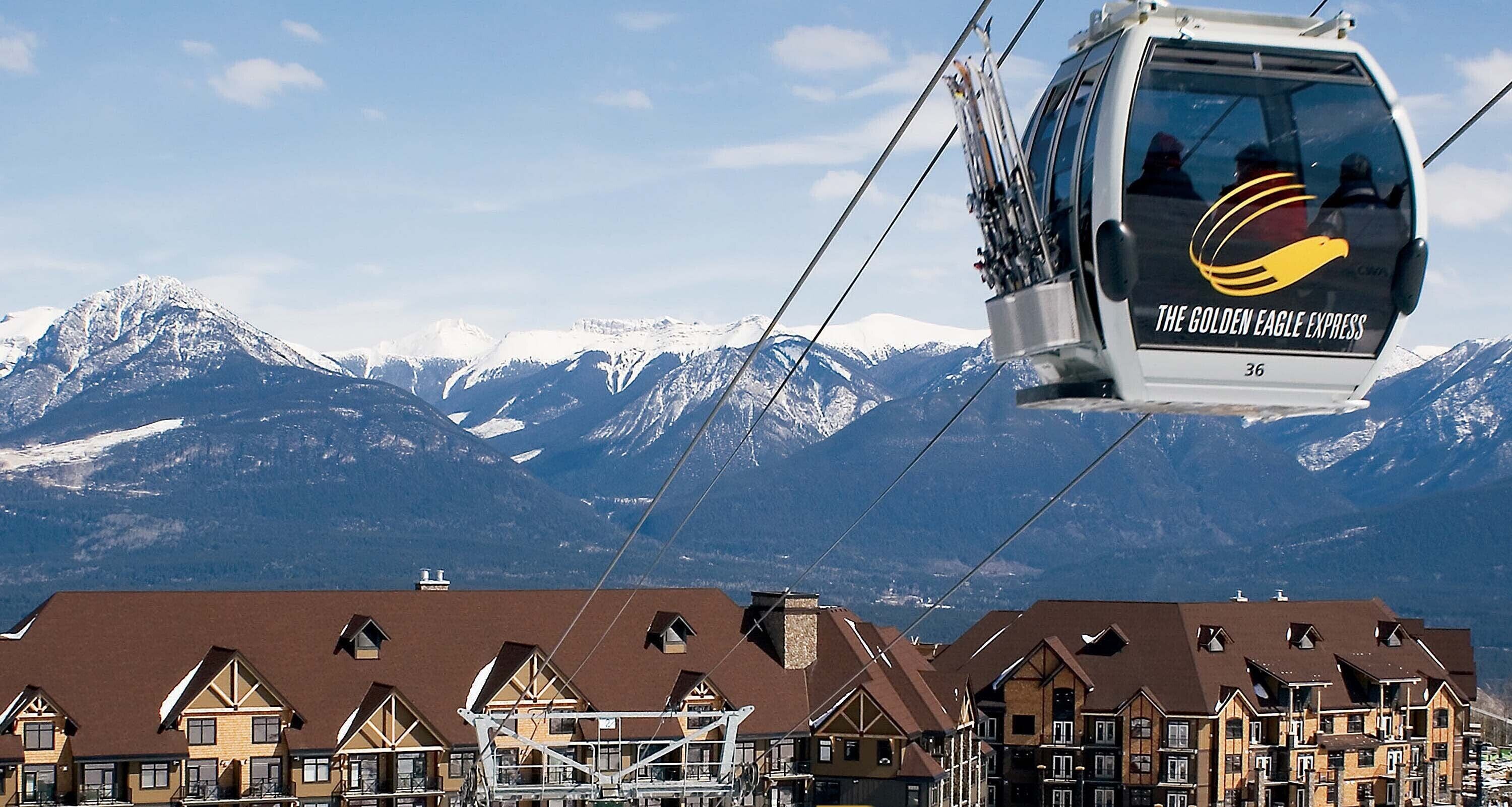 A cable car with "THE GOLDEN EAGLE EXPRESS" branding, a mountainous backdrop, and traditional chalet-style buildings.