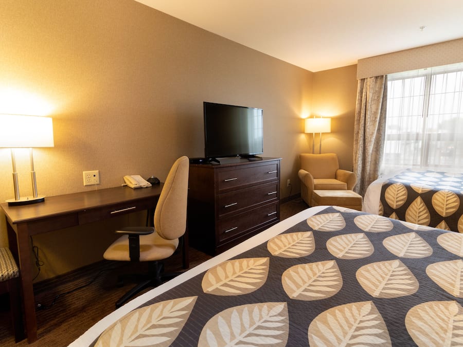 A hotel room with a bed, desk, chair, TV, and two lamps.