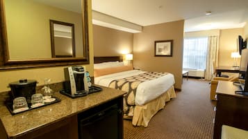 Una habitación de hotel con cama, escritorio, cafetera y espejo.