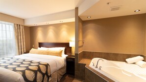 A hotel room with a large bed, a separate bathroom with a bathtub, and a window with curtains. - The Kanata Inn Fort Saskatchewan (Fort Saskatchewan)