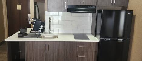 A modern kitchen with a built-in dishwasher, a refrigerator, and a coffee machine.