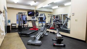 A gym with treadmills, elliptical machines, and a water cooler.