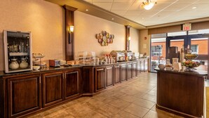 A hotel breakfast area with a long counter, buffet setup, and a view of the outside.