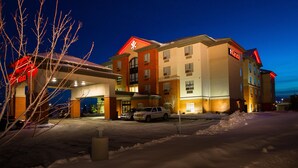 A multi-story hotel with a red and white sign, a gas station, and parked cars. - The Kanata Inn Fort Saskatchewan (Fort Saskatchewan)
