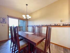 Un comedor con una mesa y sillas de madera, un candelabro y vistas al exterior.