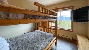 A bunk bed room with a TV on the wall and a window with a mountain view. - Whispering Pines (Golden)