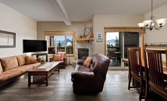 Una sala de estar con chimenea, un sofá, un sillón reclinable, un televisor y una zona de comedor con sillas.