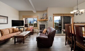 A living room with a fireplace, a sofa, a recliner, a TV, and a dining area with chairs.