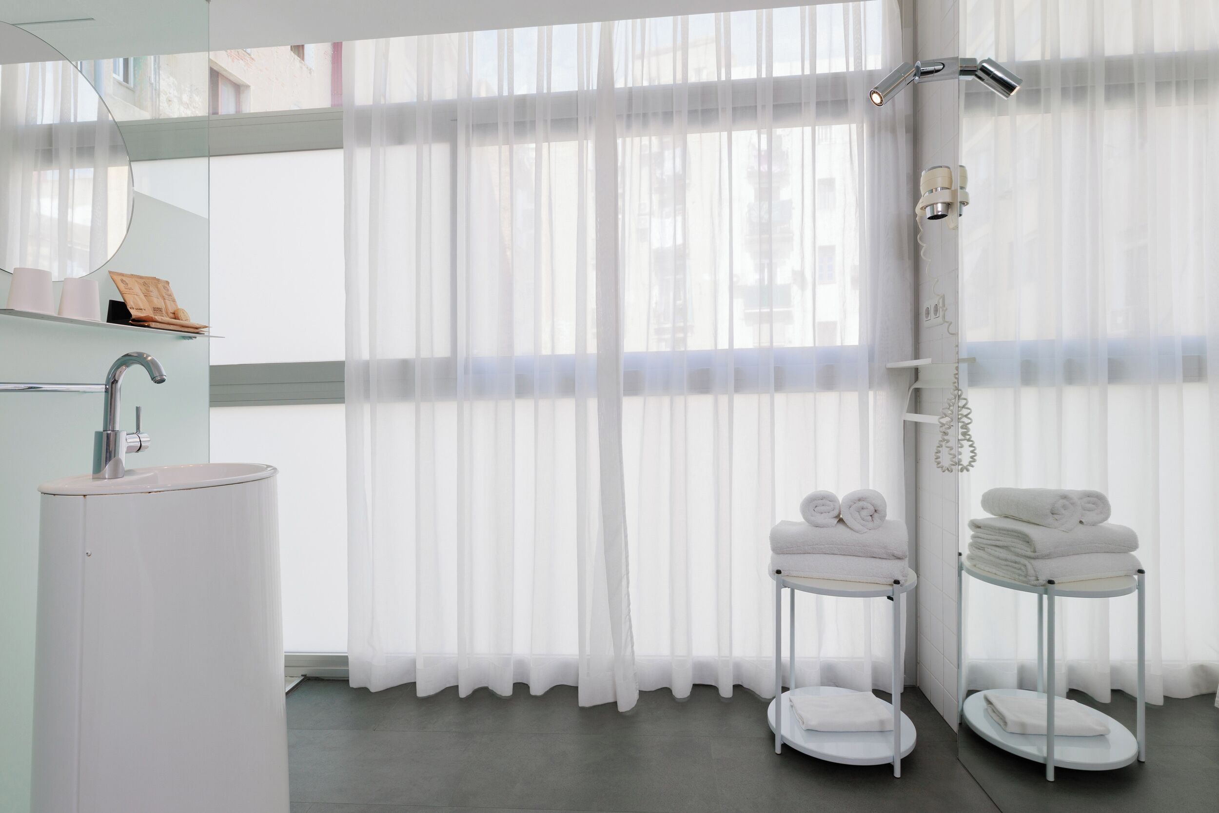 Un baño moderno con un ventanal grande, un lavamanos y una ducha.