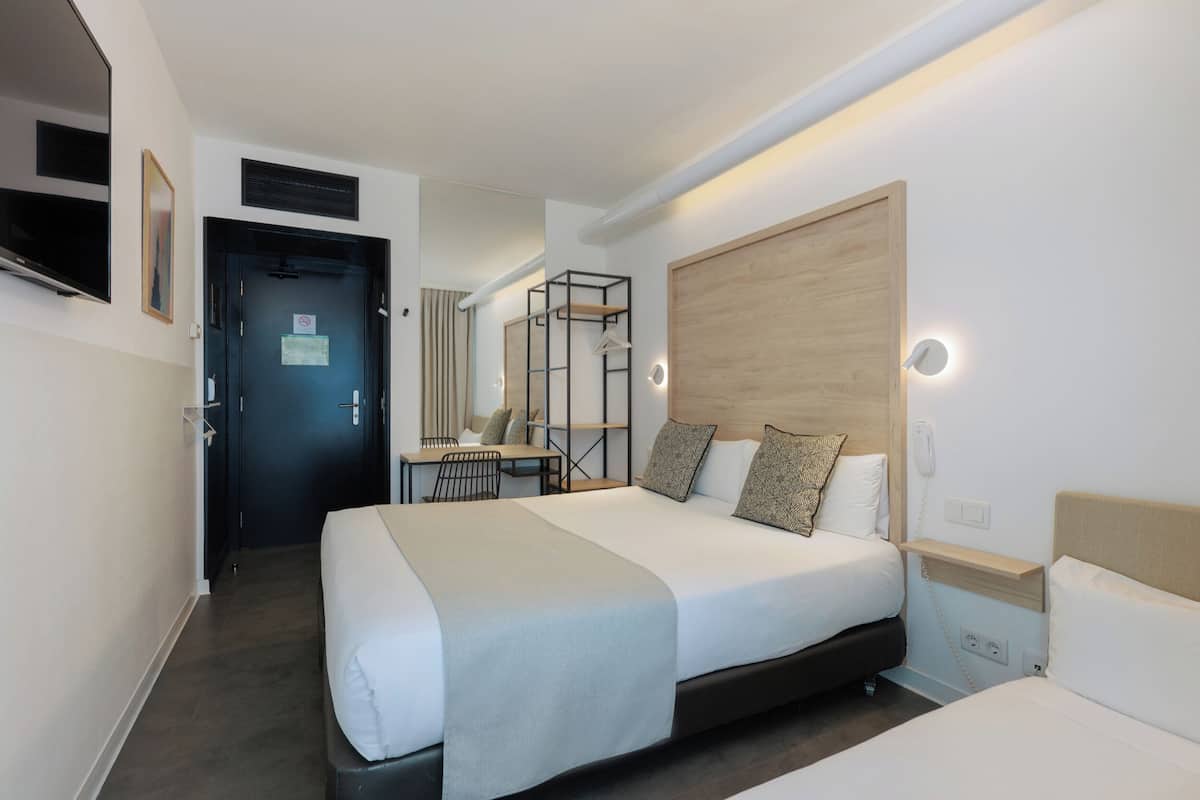 A hotel room with a large bed, a desk, and a chair.