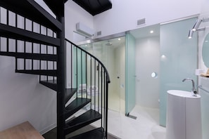 A modern bathroom with a glass-enclosed shower, a white sink, and a black staircase. - Casa Lit Barcelona (Barcelona)