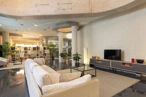 A spacious lobby with a sofa, coffee table, and a TV on a cabinet. - Casa Lit Barcelona (Barcelona)
