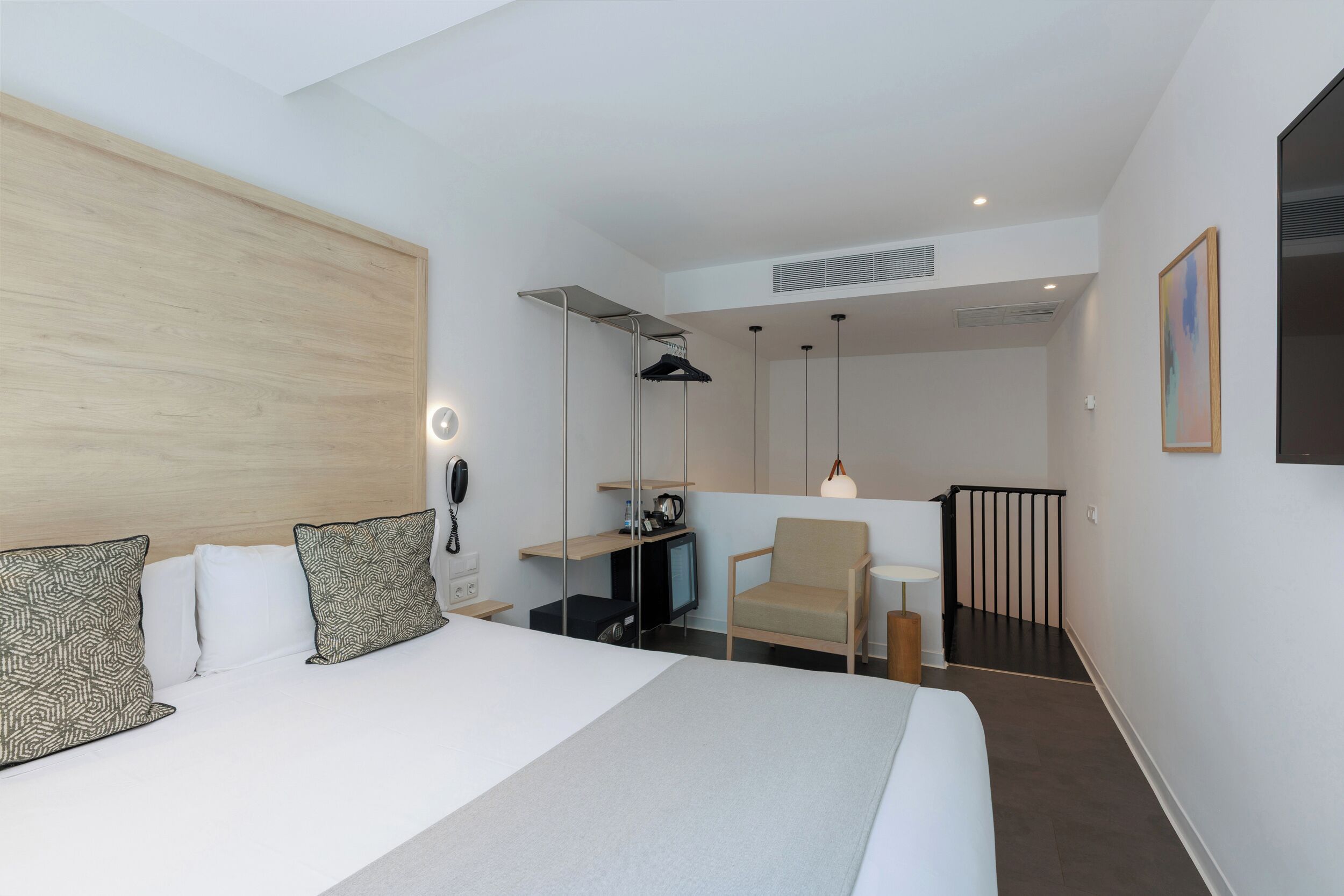 Een hotelkamer met een groot bed, een bureau met een computer, een stoel, een televisie en een klein tafeltje met een lamp.