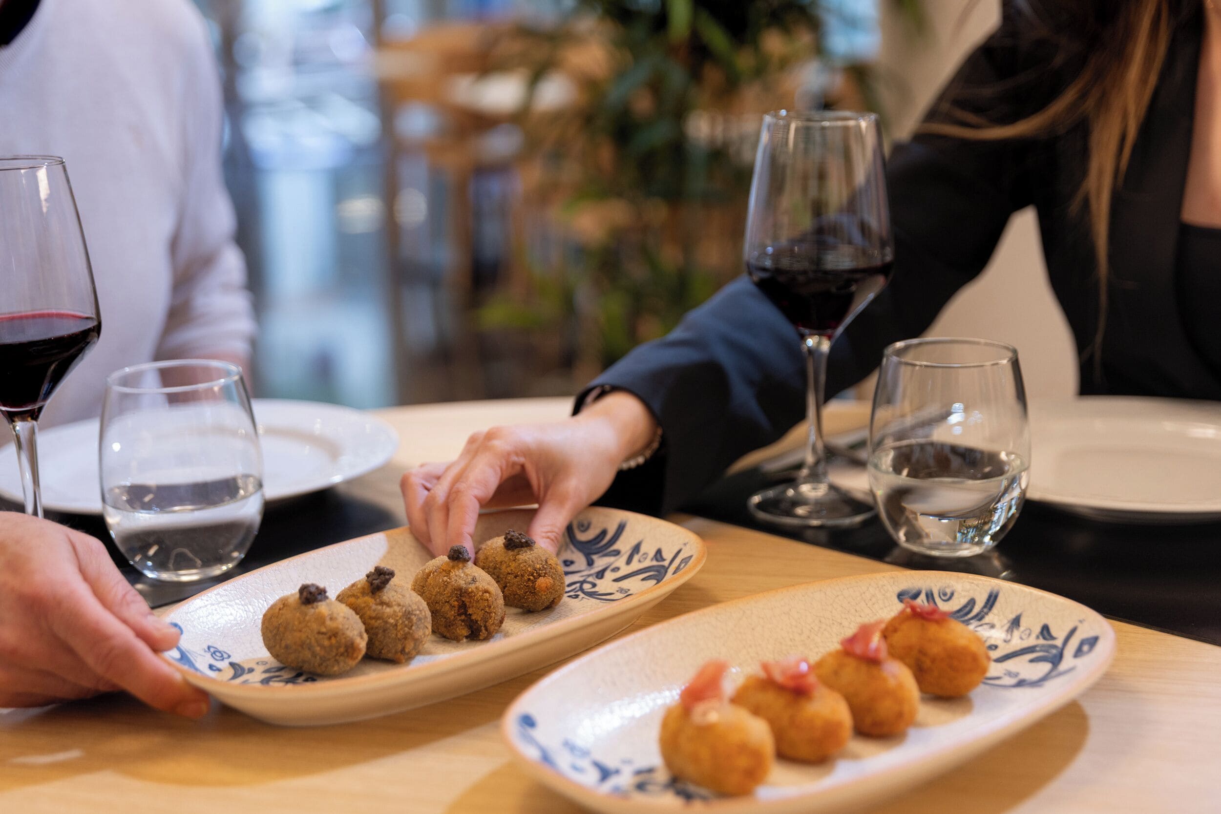 A dining table with plates of food and glasses of wine.