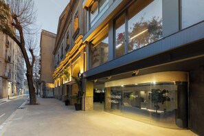 A modern building with a glass facade, a 'Welcome home' sign, and a parking sign. - Casa Lit Barcelona (Barcelona)