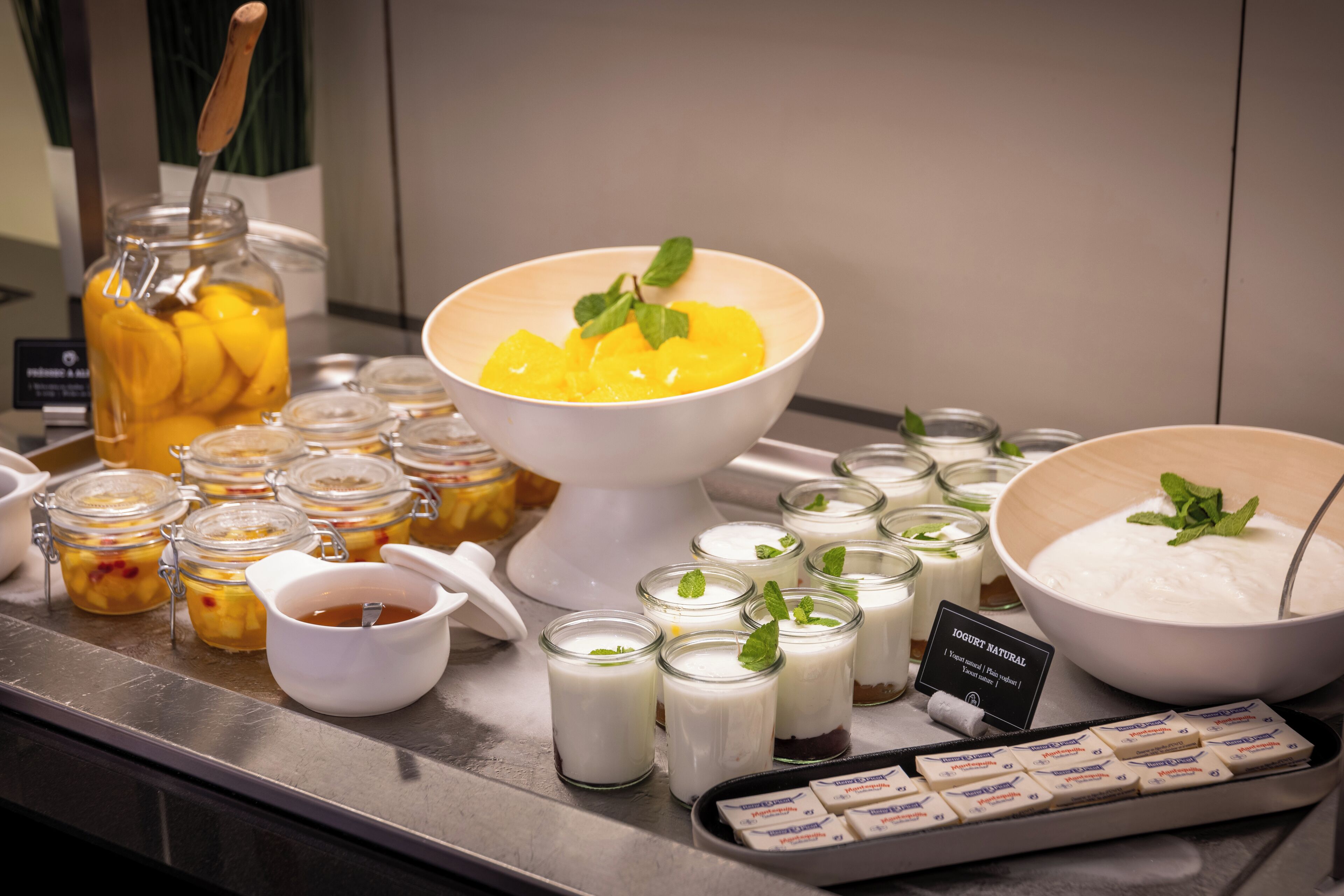 Un bufé con diversos alimentos, incluyendo tazones de yogur, fruta y salsas.