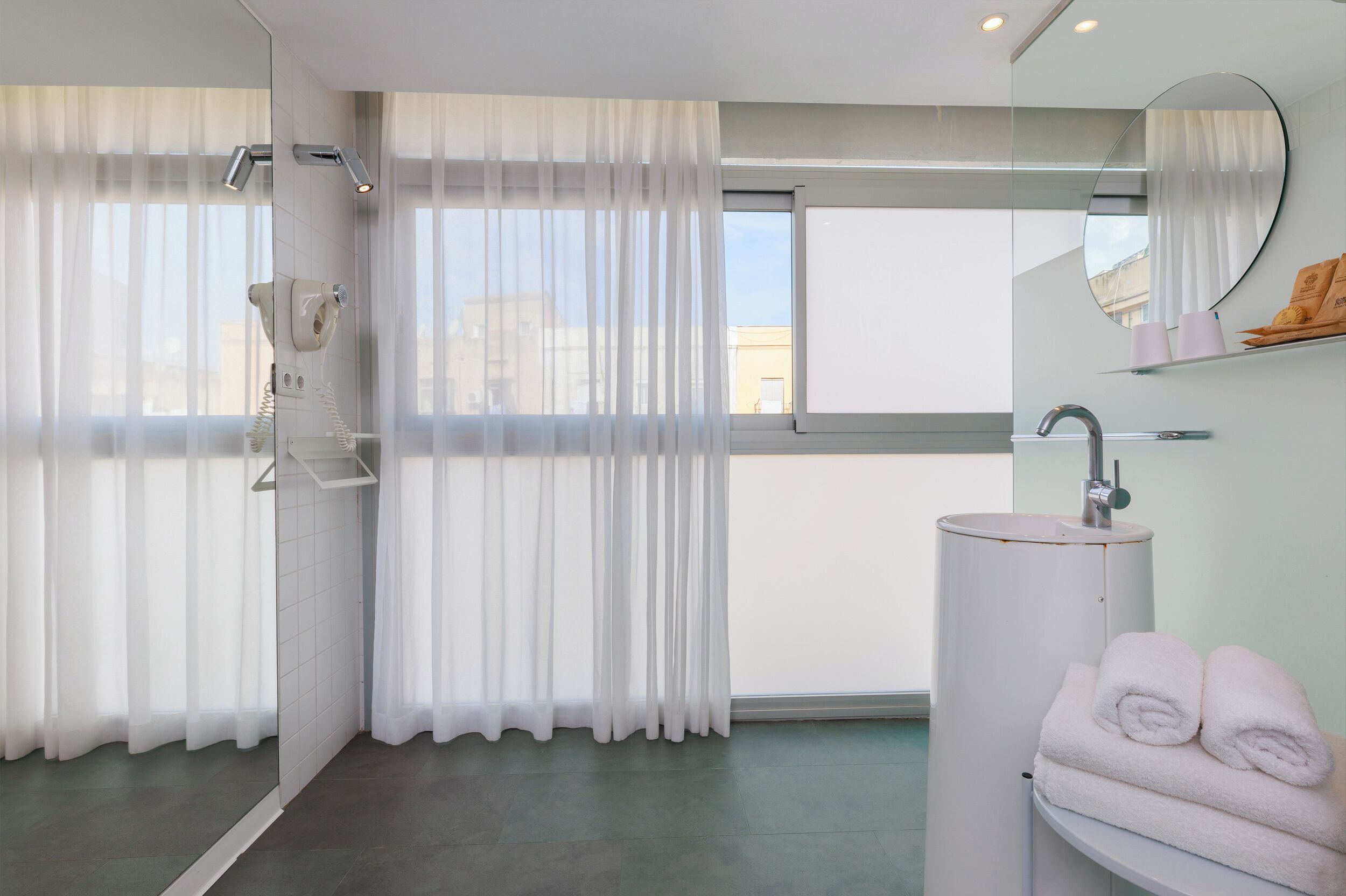Un baño moderno con cabina de ducha de vidrio, un lavamanos blanco y un espejo grande.