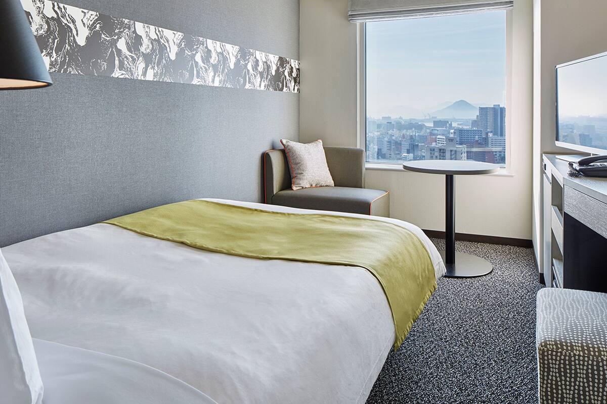 Una habitación de hotel con una cama, una silla, una mesita y un televisor.