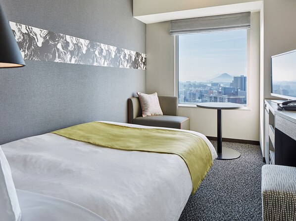 A hotel room with a bed, a chair, a small table, and a TV. - Mitsui Garden Hotel Hiroshima (Hiroshima)