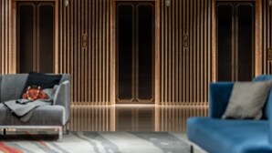 A modern interior with a sofa and a blue armchair facing a wall with vertical wooden slats and a door. - Mitsui Garden Hotel Hiroshima (Hiroshima)