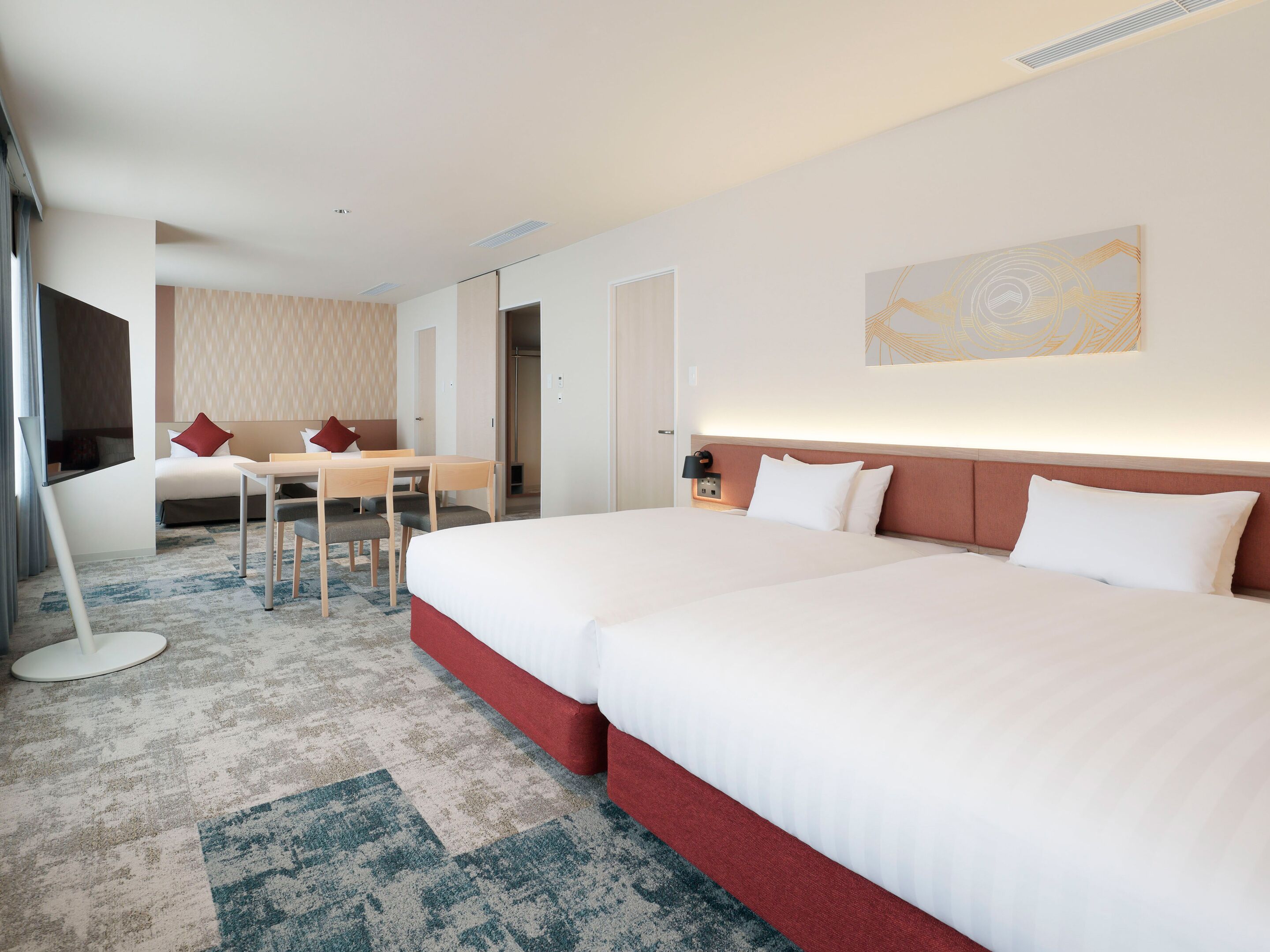 A hotel room with two beds, a desk, and a TV.