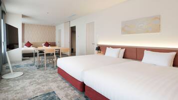 A hotel room with two beds, a desk, and a TV.