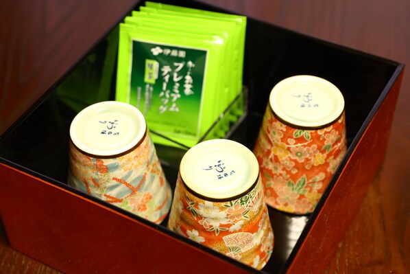 A box containing three containers with floral designs and a green packet.