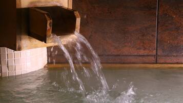 A water feature with a wooden structure and a tiled wall in the background.