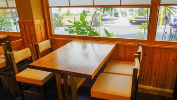 A restaurant with wooden tables and benches, large windows with a view of the street.