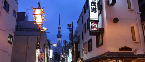 A narrow street with traditional Japanese architecture, including a lantern and signage for a cafe.