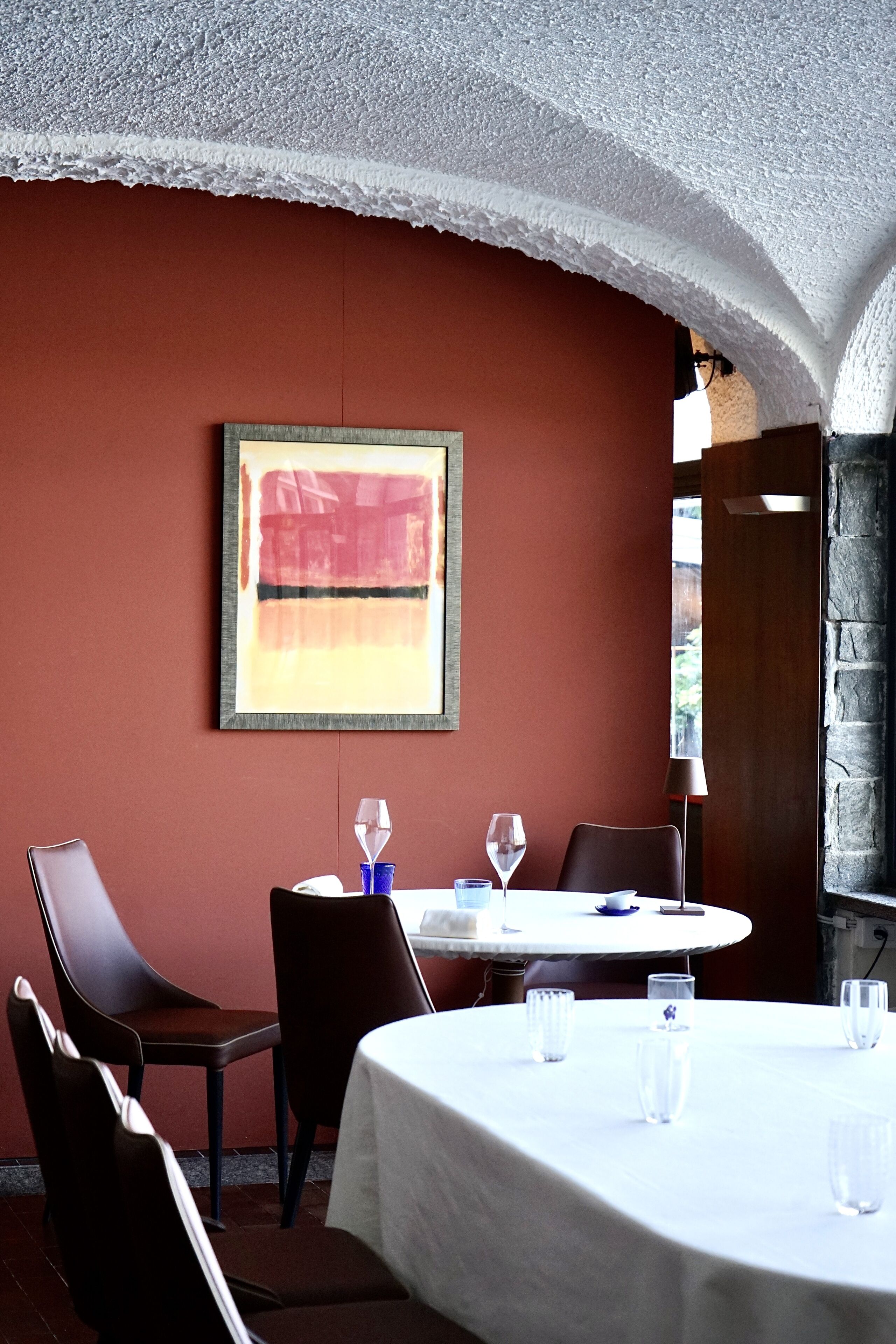 Ein Essbereich mit einem runden Tisch, Stühlen und einem gerahmten, abstrakten Gemälde an der Wand.