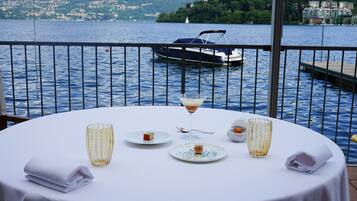 Mesa lista para comer con vista a un lago y un barco al fondo.