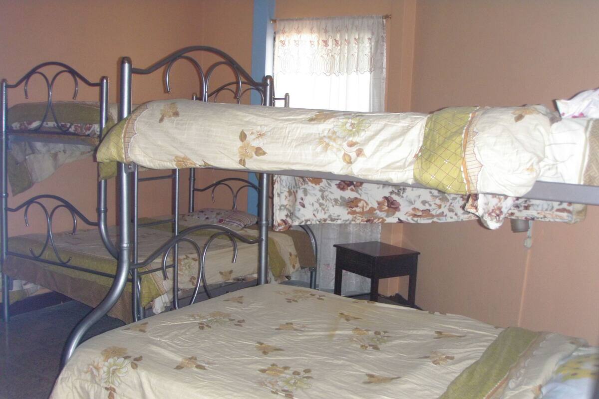 Camera con letto a castello, biancheria da letto floreale e un piccolo comodino in legno.