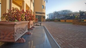 Une cour avec un chemin pavé, des plantes en pot et un bâtiment doté de balcons.